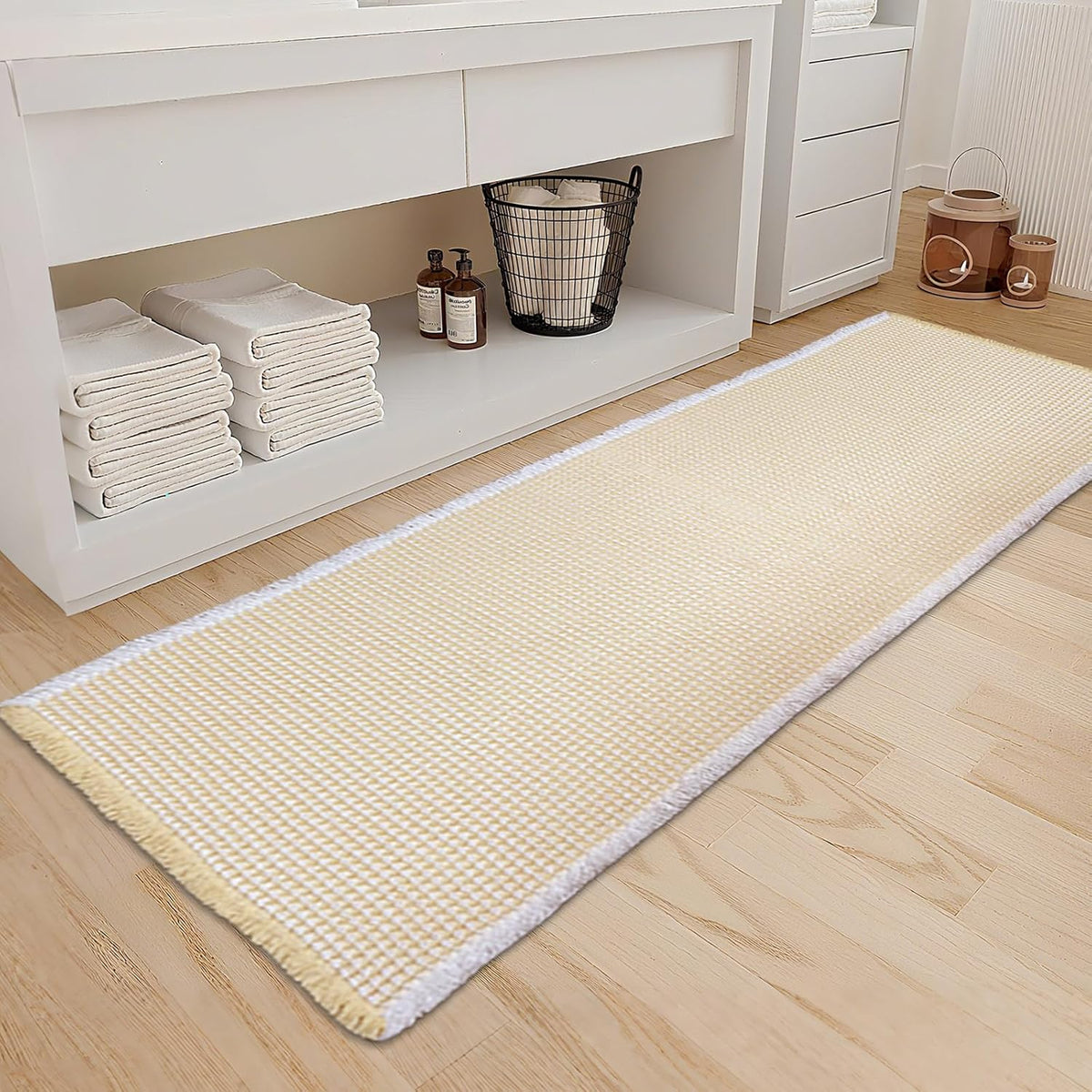 Tan waffle runner-style bath mat in front of a white vanity with folded towels