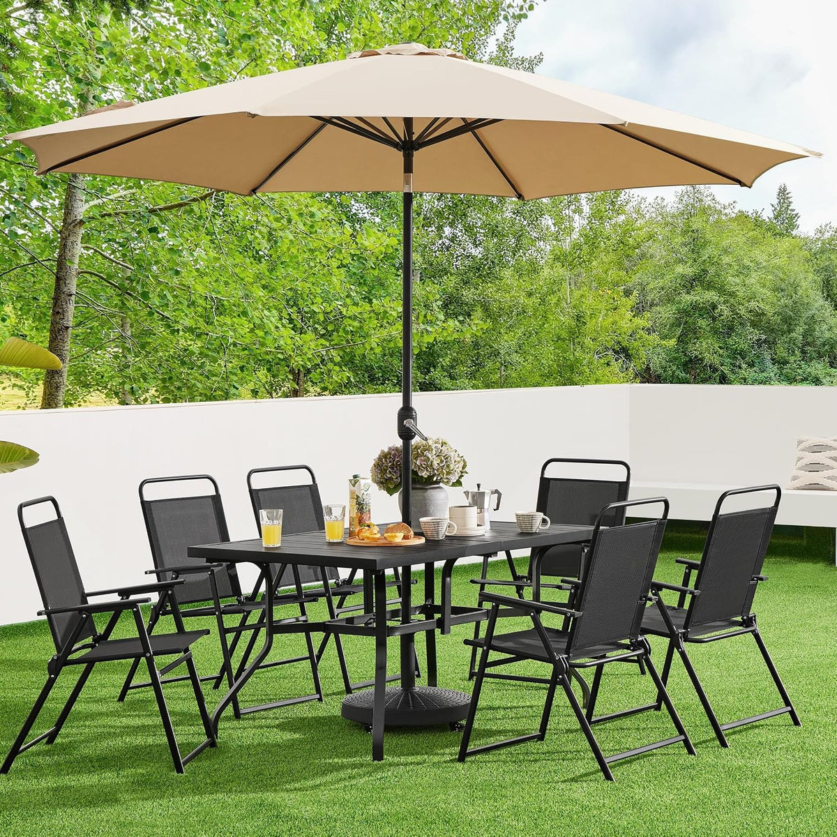 Multiple black Texteline patio chairs arranged around outdoor dining table under umbrella on lawn