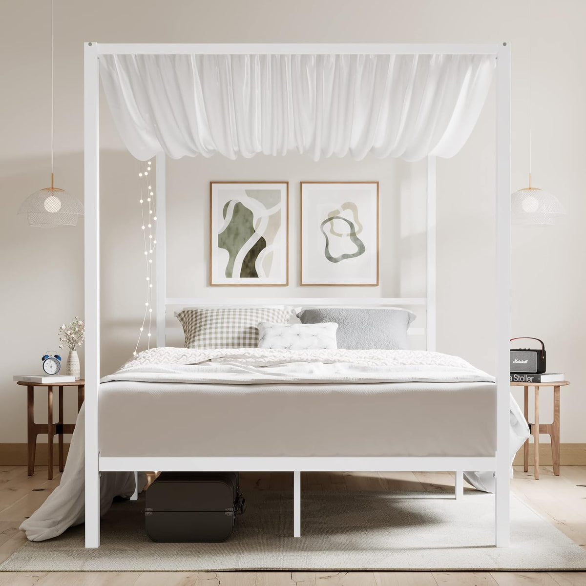 Front-facing view of a white metal canopy bed in a neutral bedroom with light drapery and bedside decor