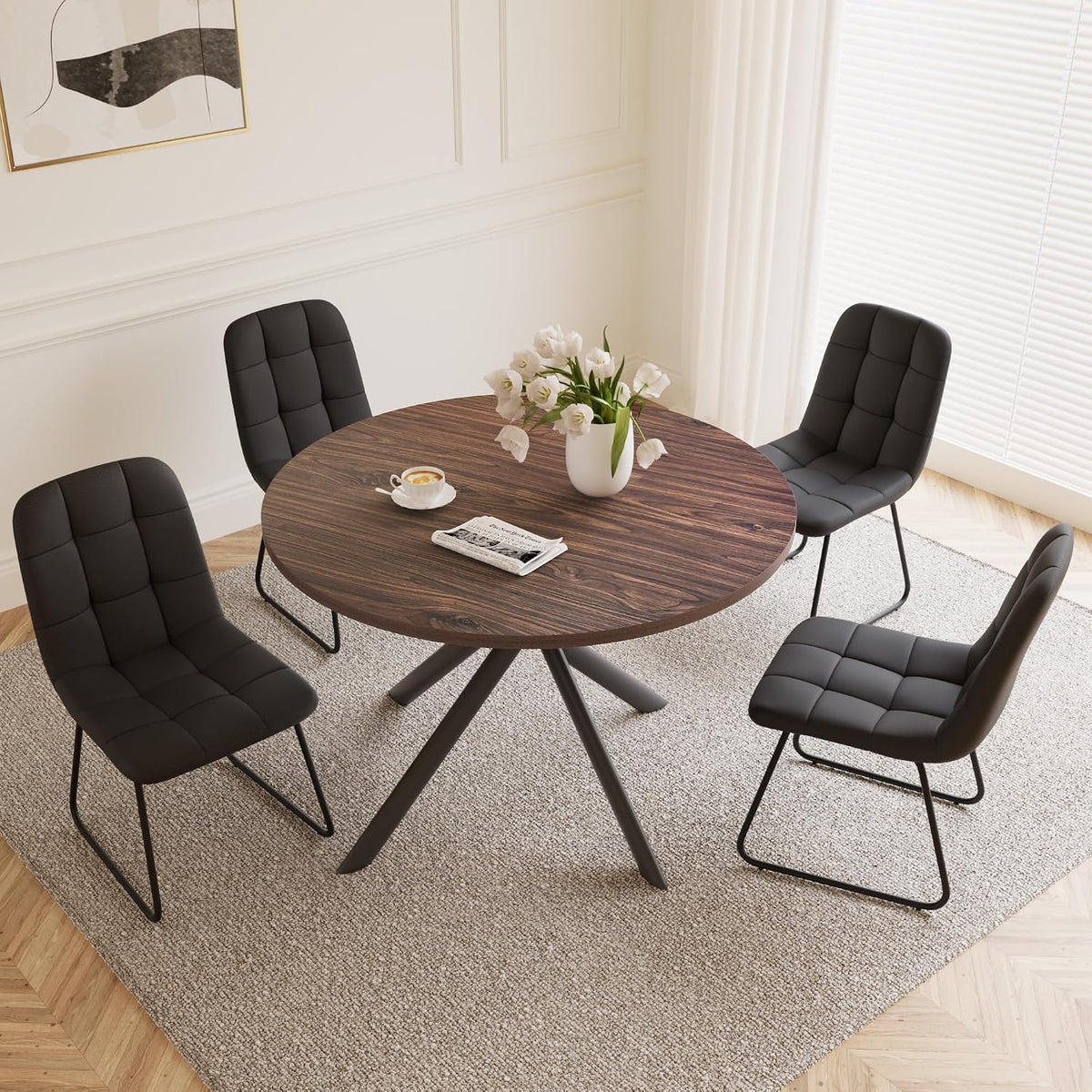 Dining setup with a round dark-walnut table and four black U-shaped chairs on a neutral rug