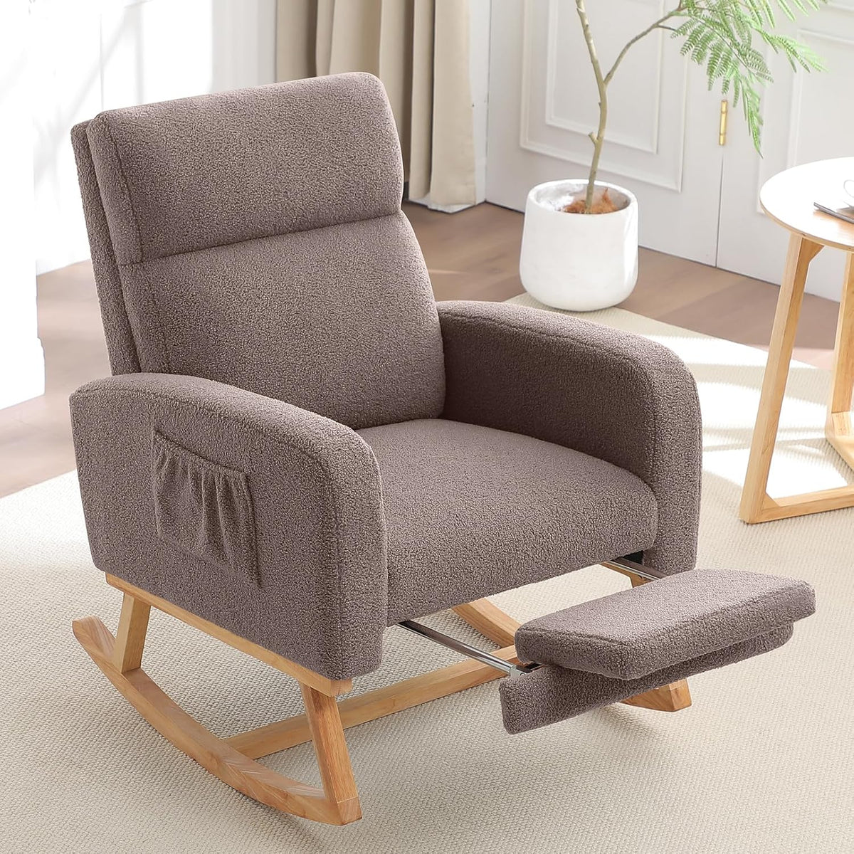 Three-quarter close-up of a taupe bouclé rocking chair with padded footrest partially extended and light wood rockers.