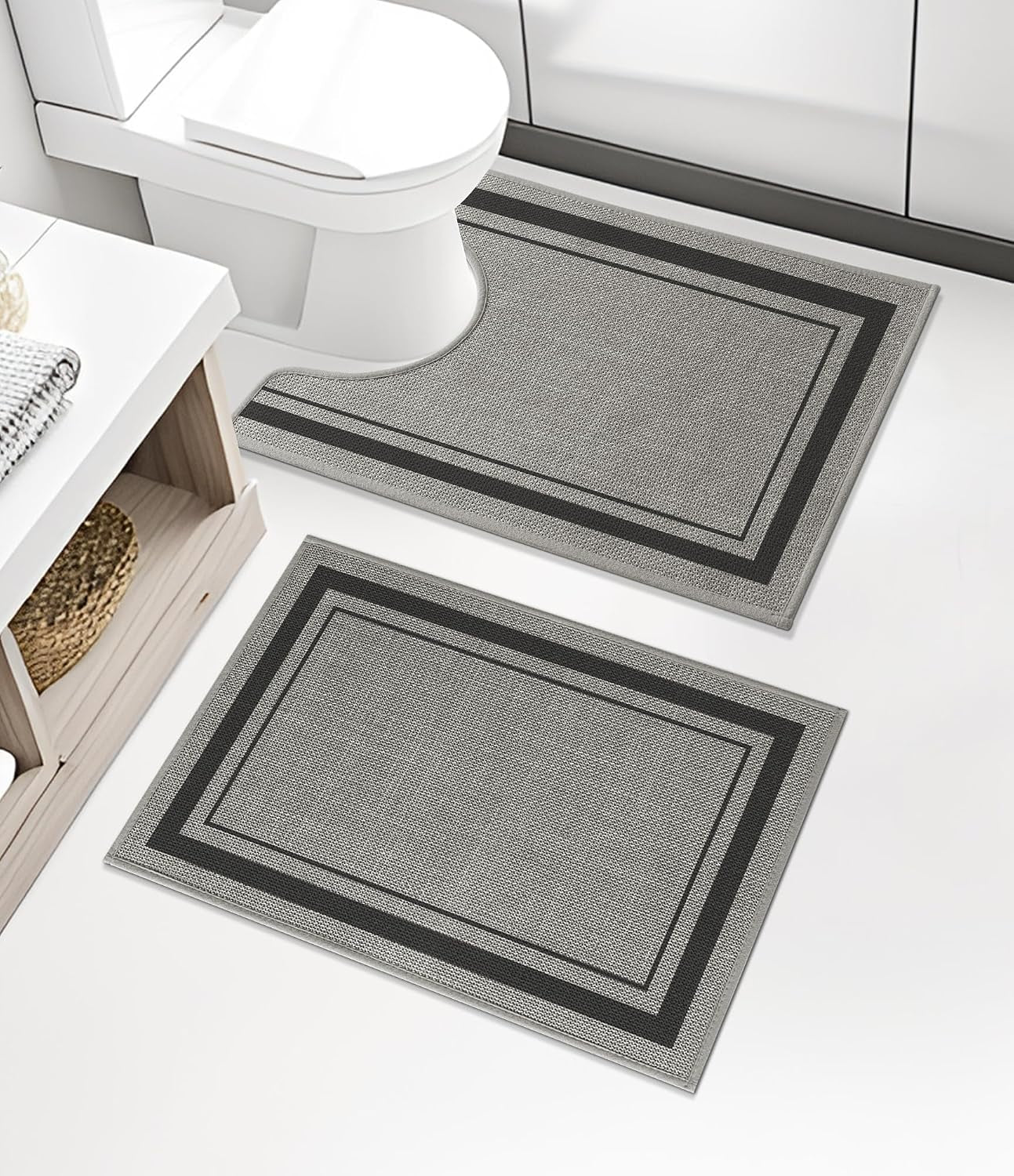 Two rectangular mats with dark inner and outer borders placed on a white floor, one positioned beneath a toilet.