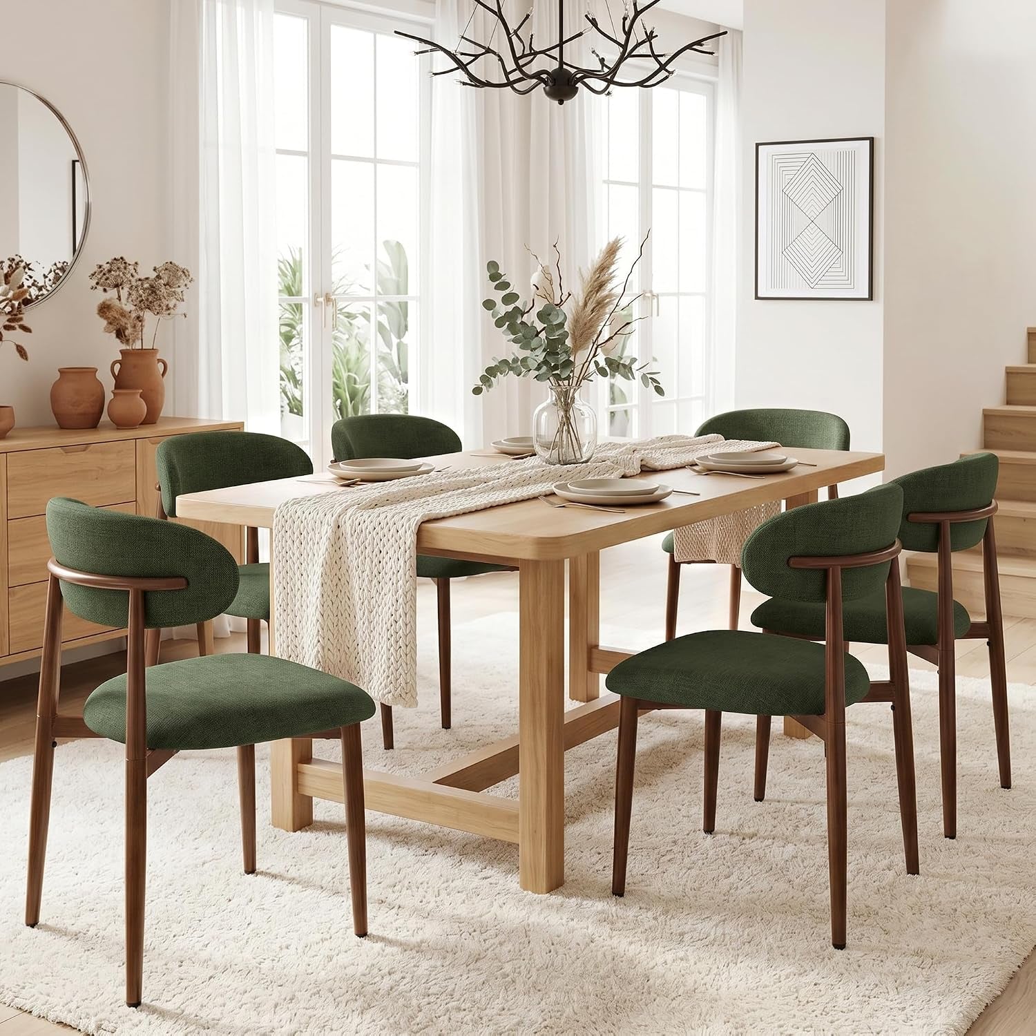 Bright dining room with six dark green upholstered chairs arranged around a light wood rectangular table on a cream rug.