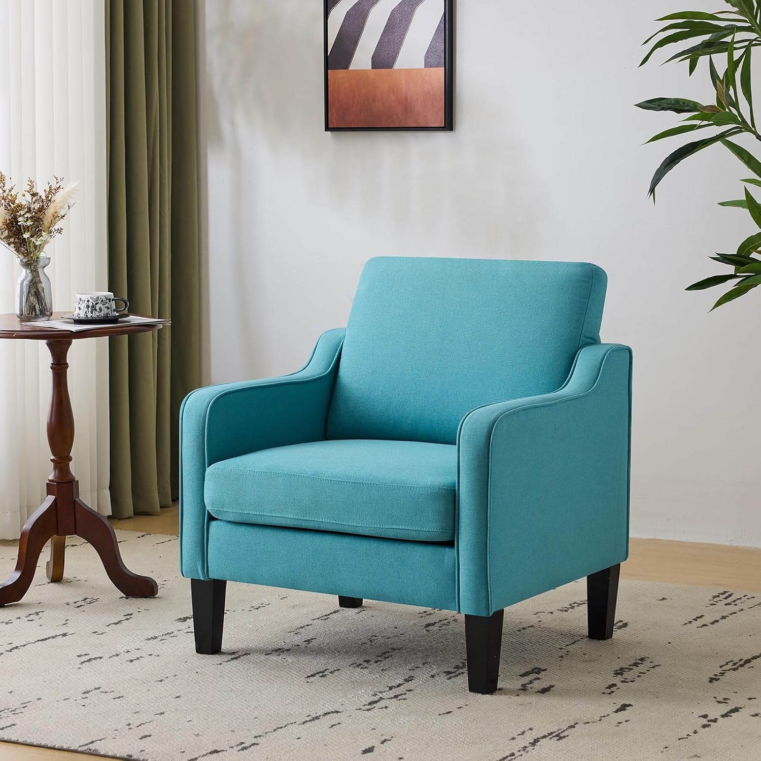 Single teal upholstered accent chair placed on a patterned rug next to a small wooden side table.