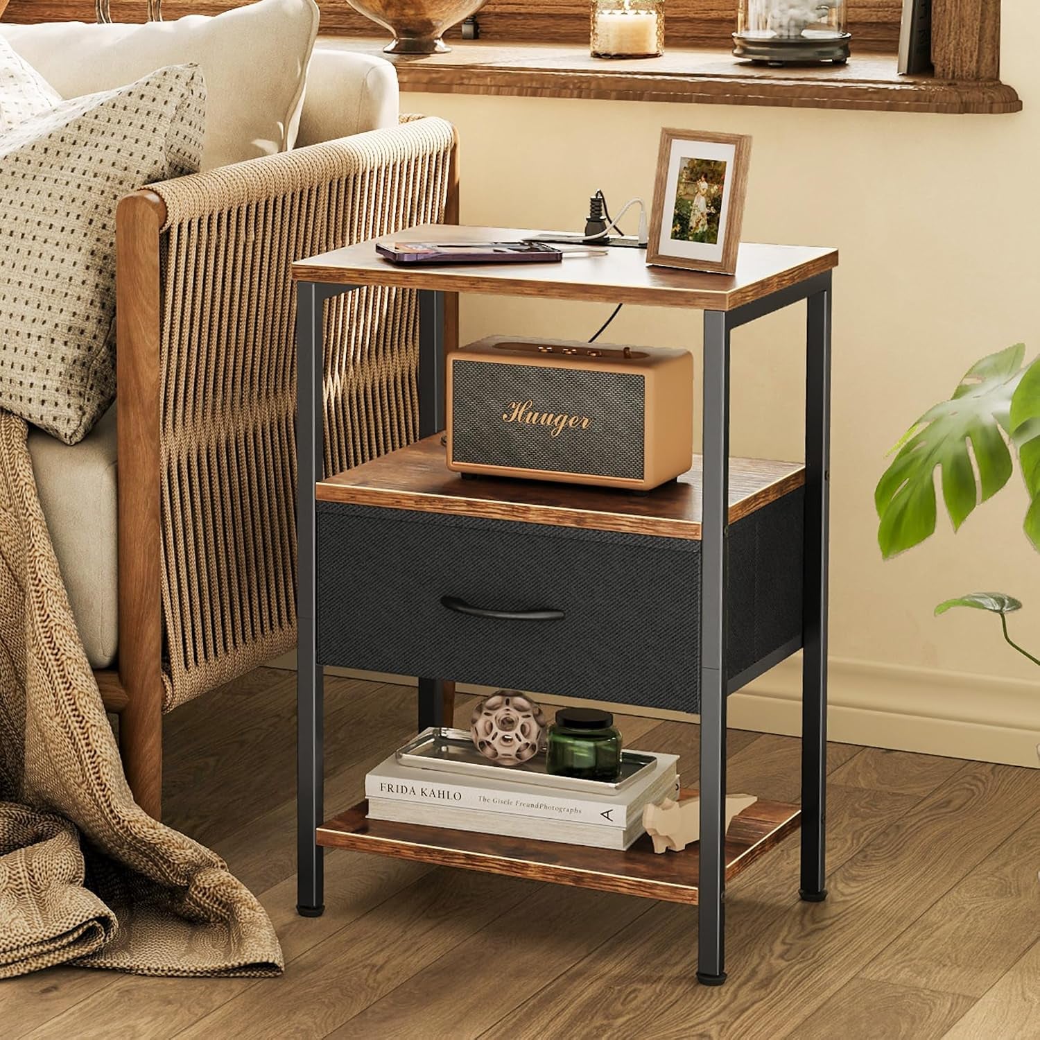 Side/front lifestyle view of the nightstand next to a woven-arm sofa showing speaker on middle shelf and lower drawer.