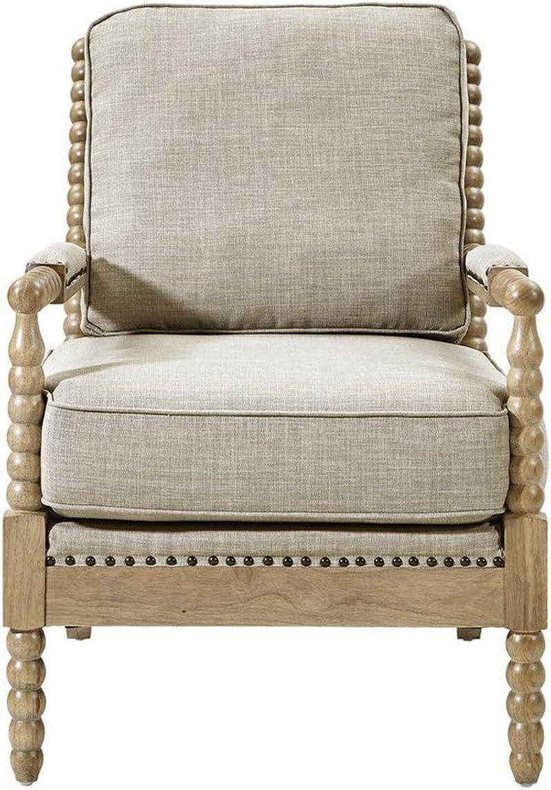 Front-facing antique-cream upholstered armchair with turned wooden bobbin legs, padded seat and nailhead trim.