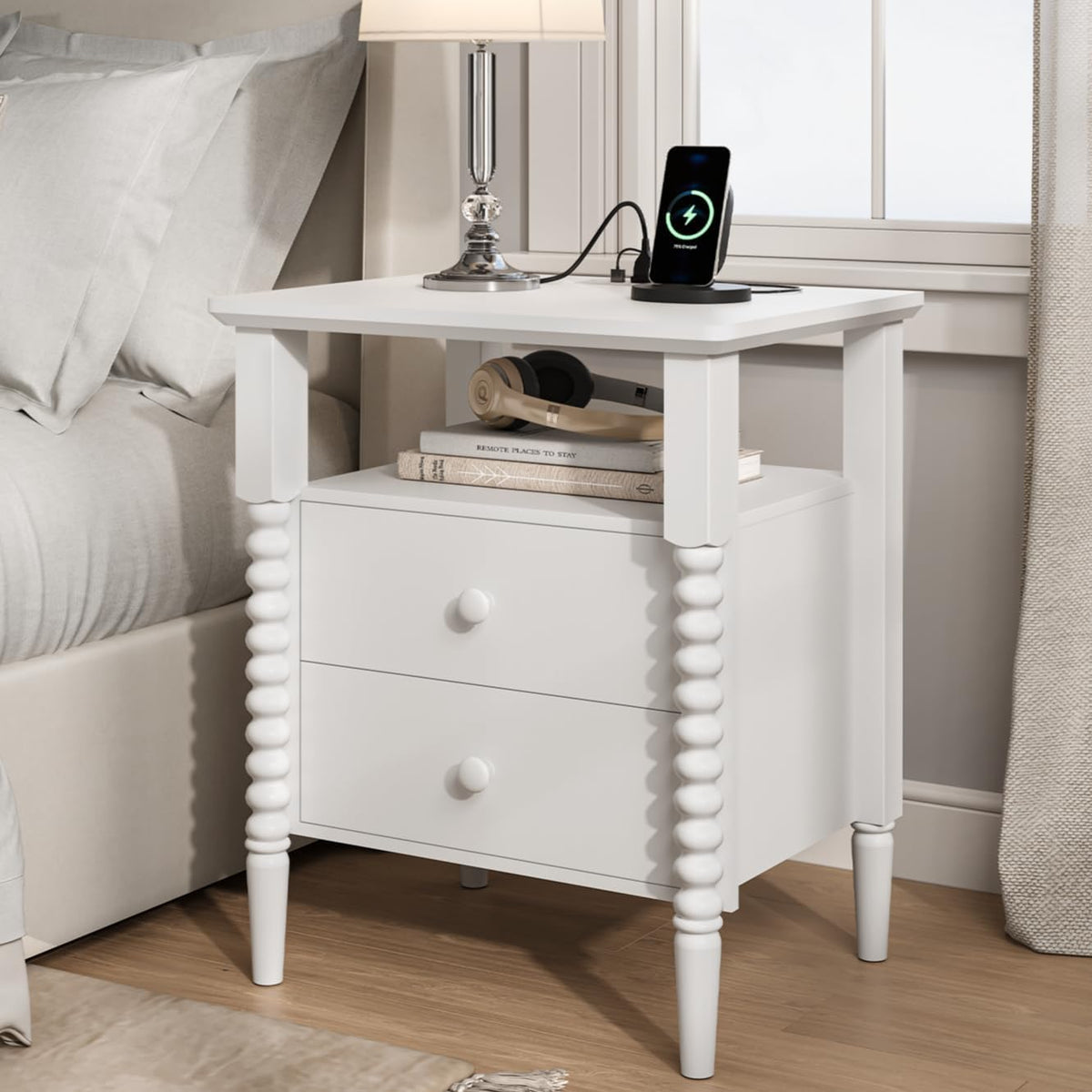 Close angled view of a white round-fluted nightstand next to a bed with lamp and wireless charger.