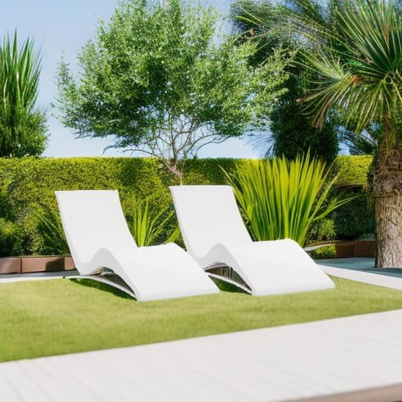Two white contoured loungers placed side-by-side on lawn beside a pool in an outdoor daytime setting