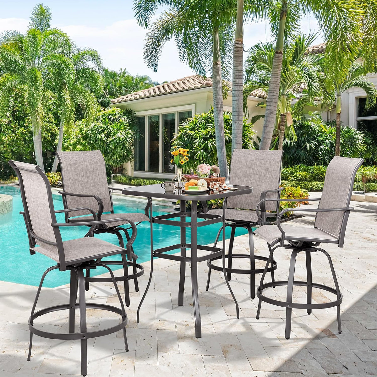 Low-angle poolside view of a taupe bar table and four swivel chairs with breakfast plates on the glass top.