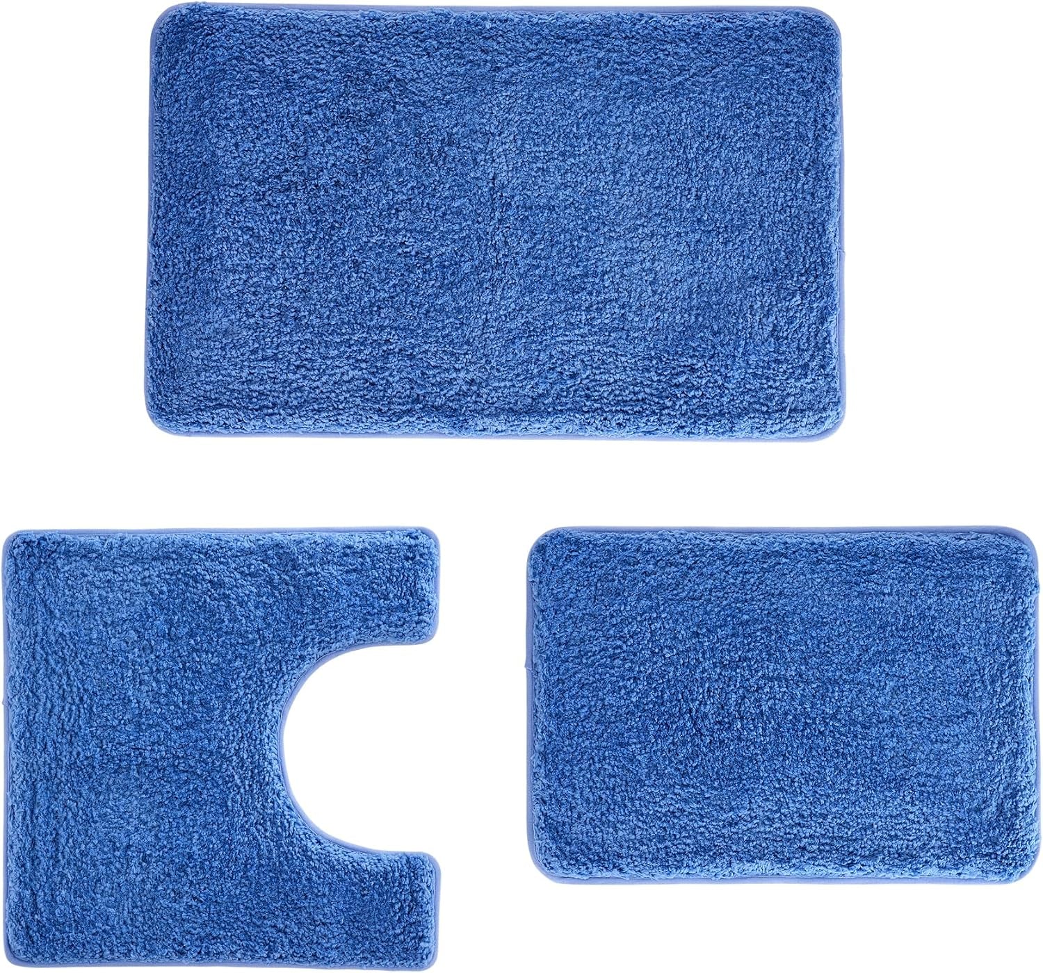Flat lay of three blue plush bathroom mats: large rectangular bath mat, U-shaped toilet mat, and matching small mat.