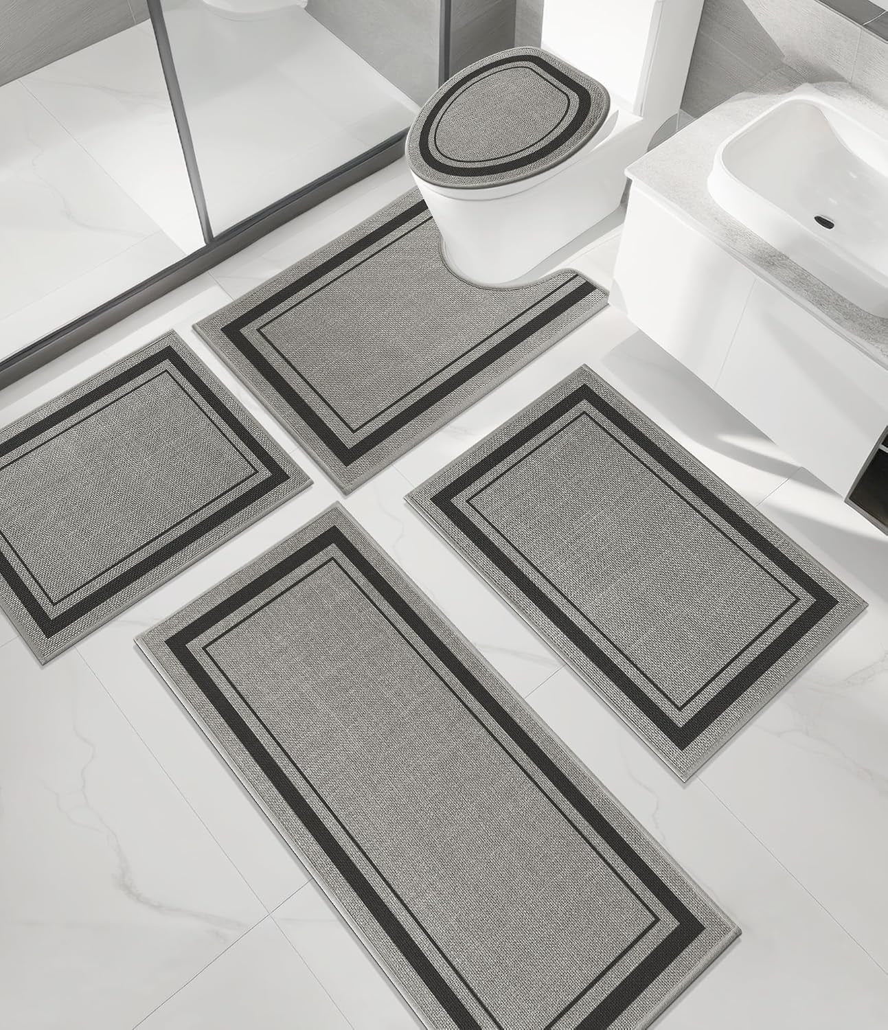 Overhead view of a bathroom showing four coordinated pieces: two rectangular mats, a toilet contour mat, and a toilet lid