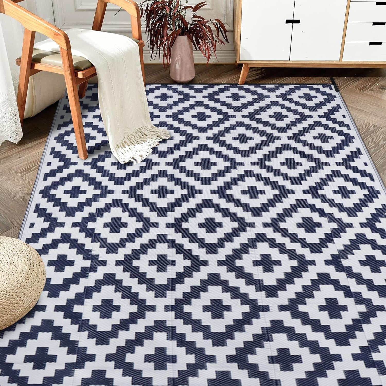 Indoor entry scene with a navy-and-white geometric rug beside a wooden chair and cabinet.