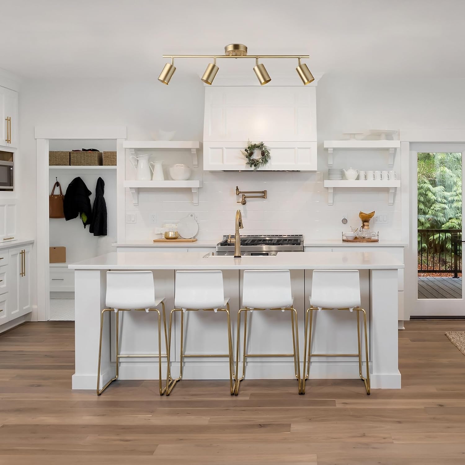 Matte brass track fixture mounted over a white kitchen island with four bar stools, showing overhead placement