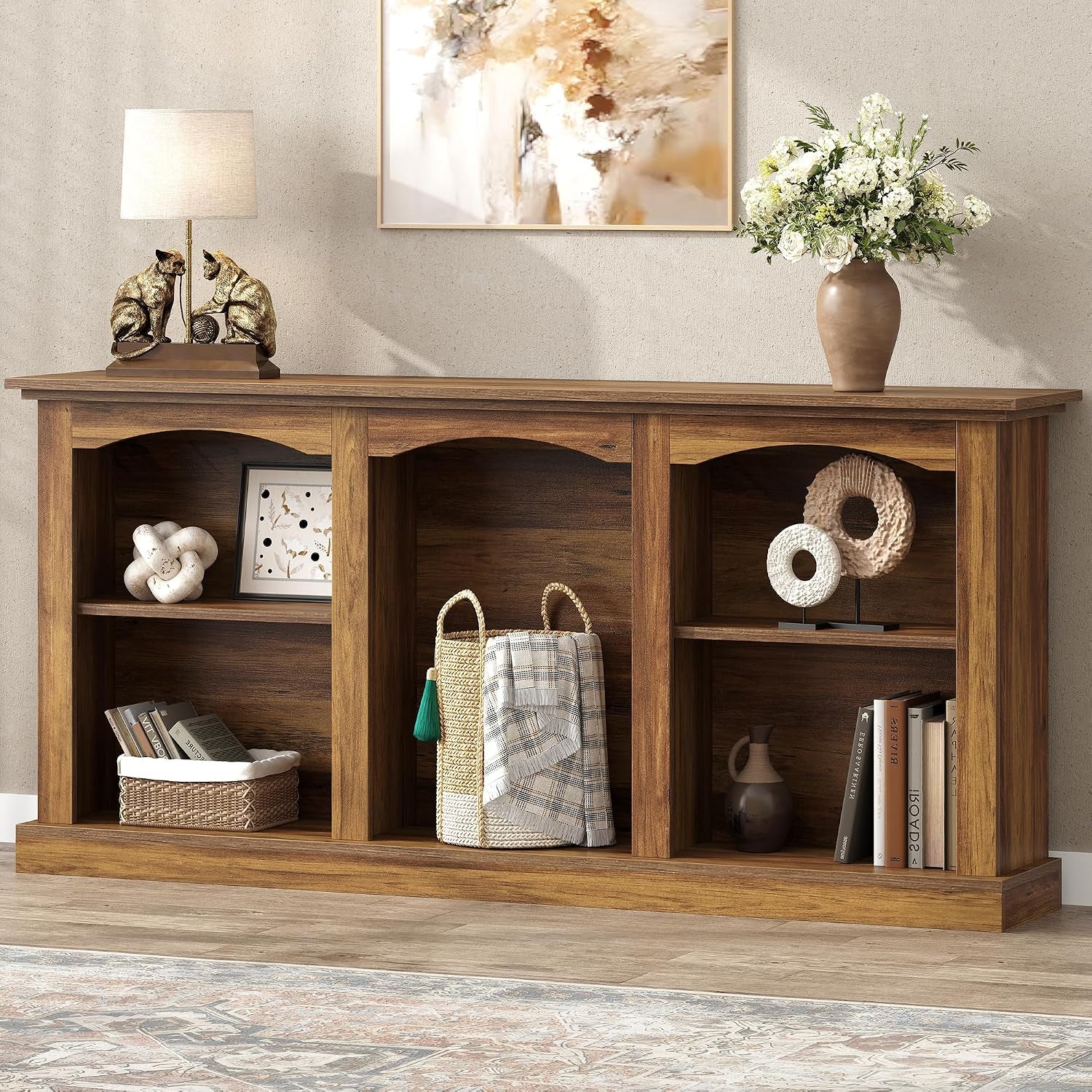 Front view of rustic brown 63-inch arched console table styled with lamp, framed art, and vase on top
