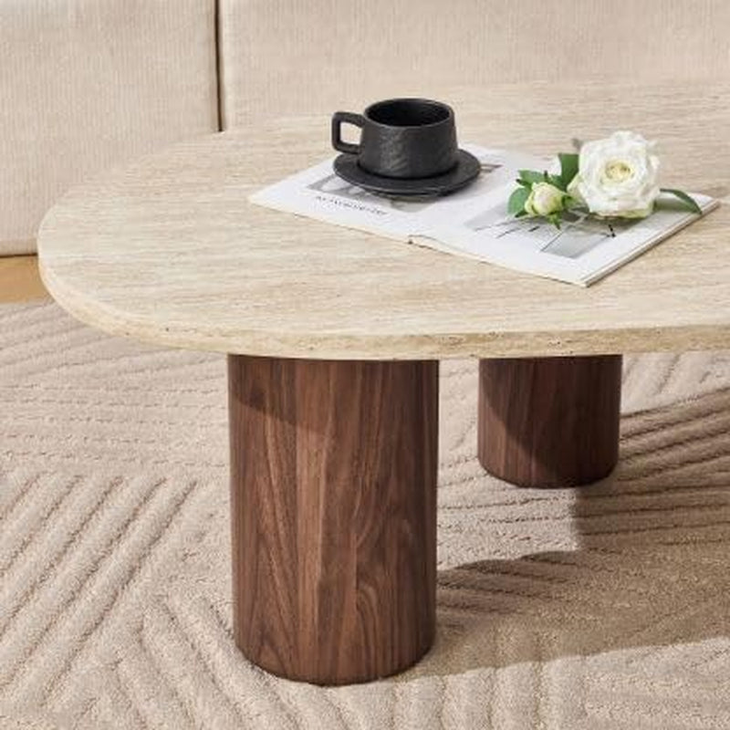 Close-up of two walnut-finish cylindrical legs under an oval light travertine-style top, black cup and white flower on