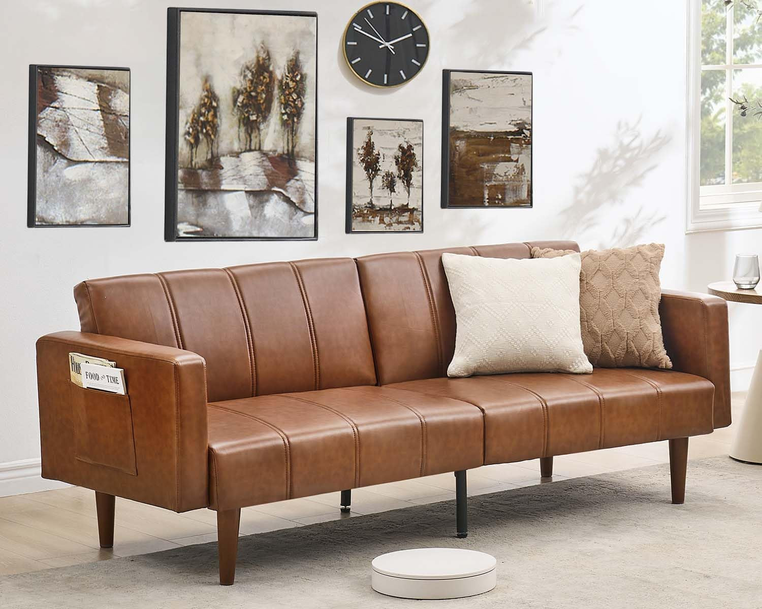Brown PU leather futon sofa angled front view with decorative pillows and wall art