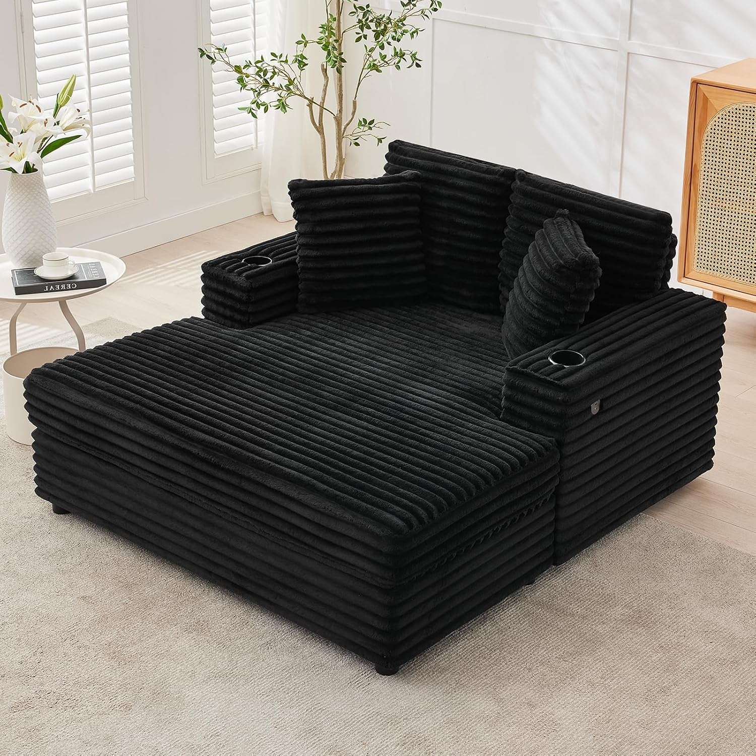 Black oversized corduroy chaise with ribbed upholstery, cup holders, and stacked cushions.