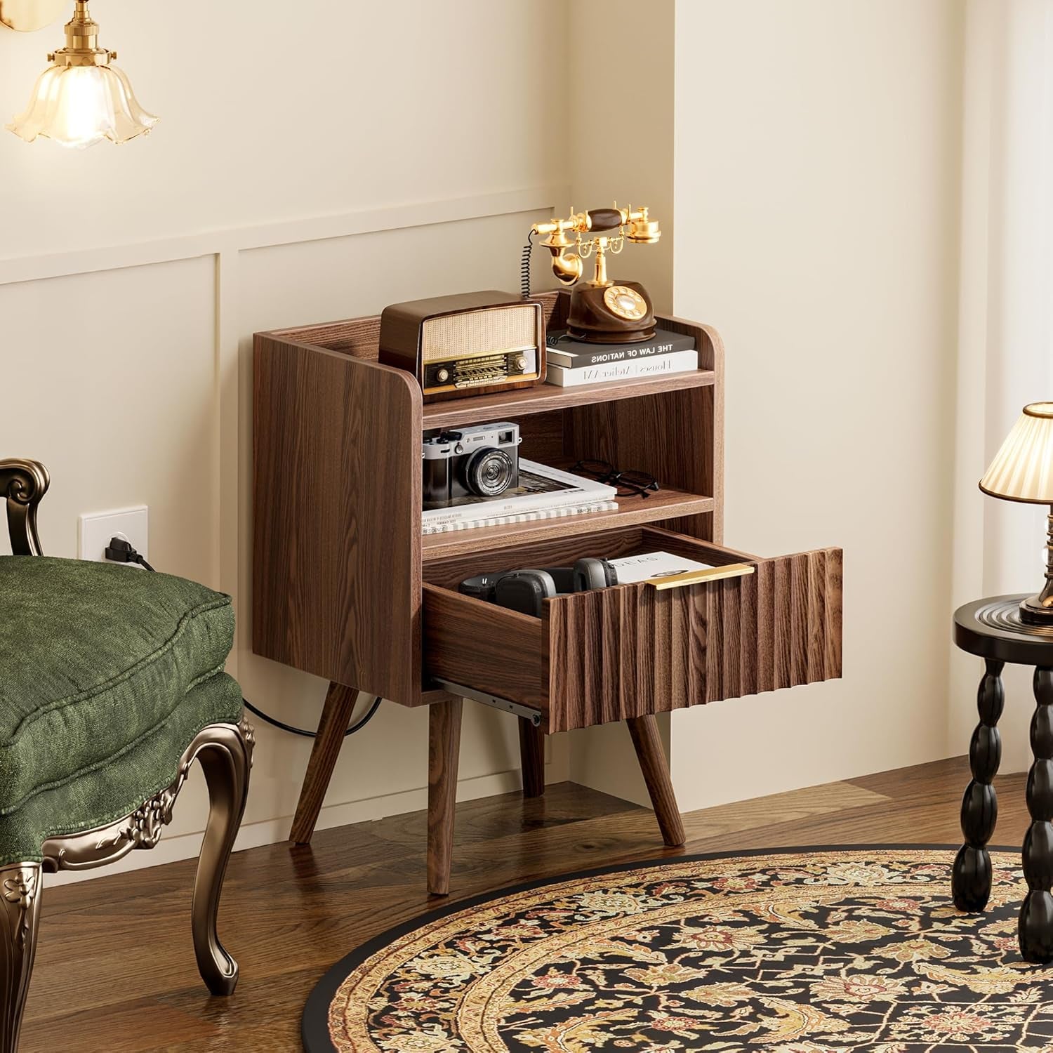 Walnut nightstand next to a green upholstered chair, drawer open showing headphones inside