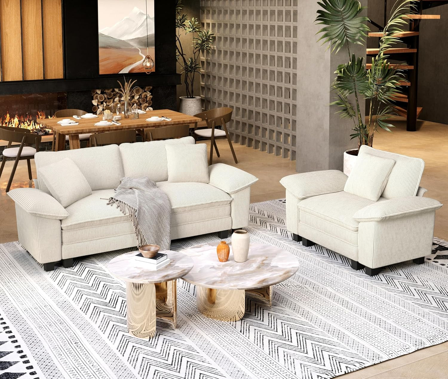 Angled view of a cream sofa and matching armchair on a patterned rug with gold-accent nested tables.