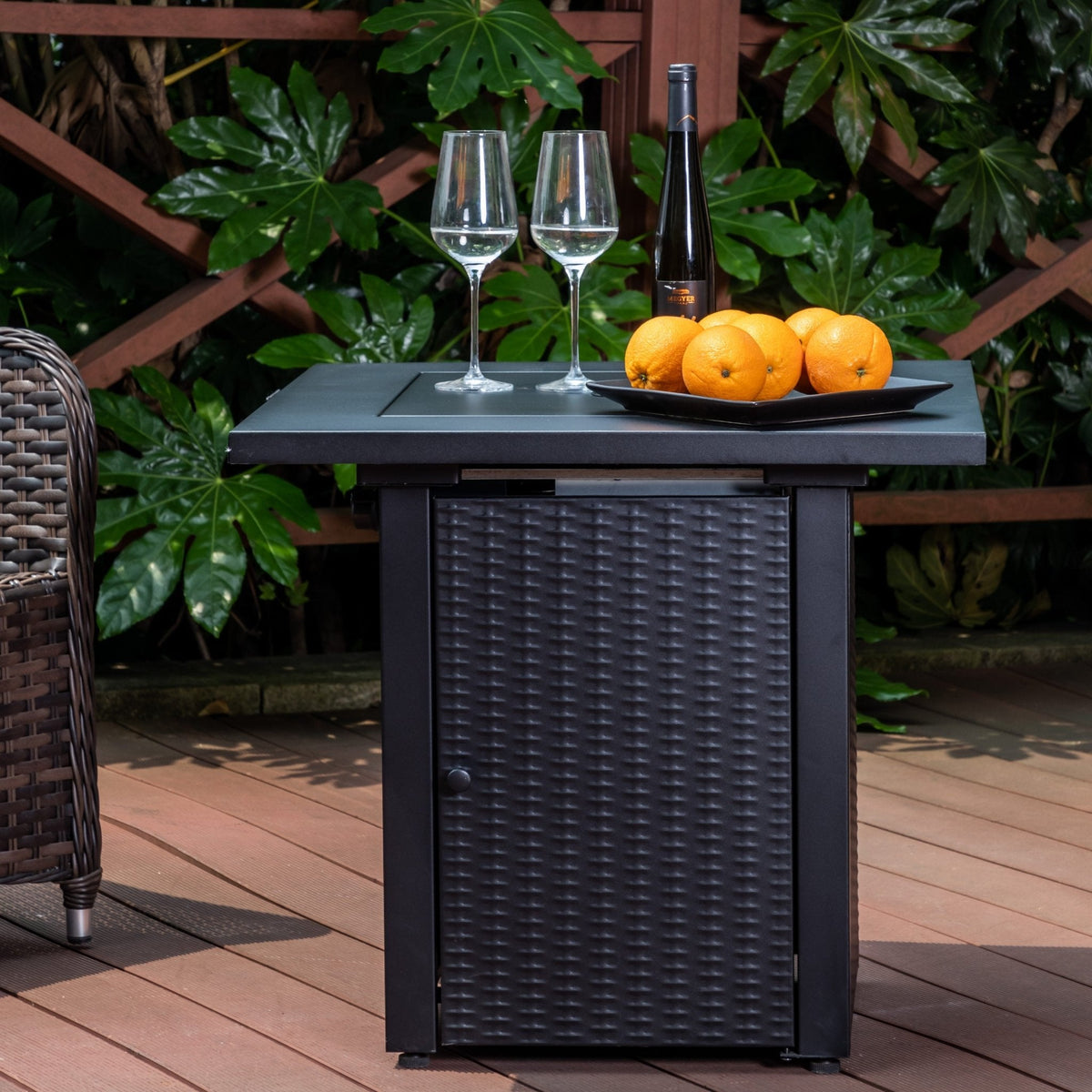 The black woven-sided table is shown with wine glasses and oranges on its covered top.