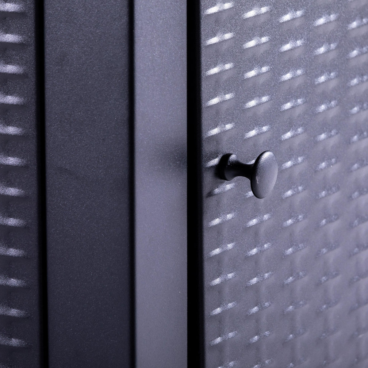 Close-up of the textured cabinet panel and its small black pull knob.