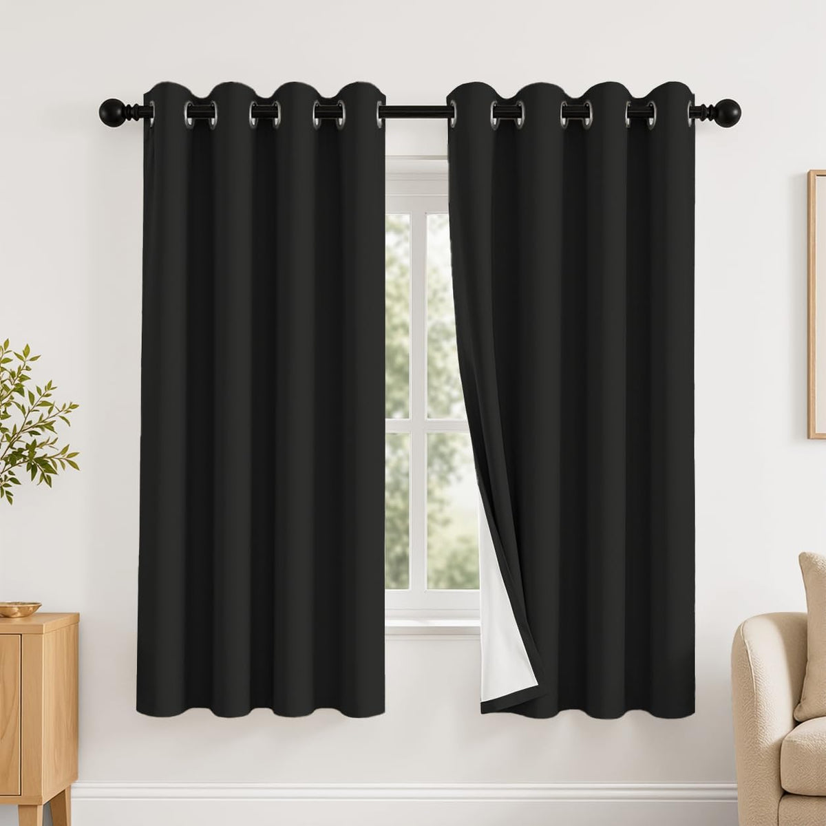 Window with two black grommet curtains, right panel pulled back showing white backing.