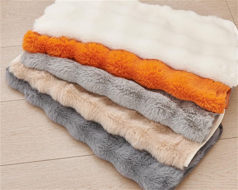 Stack of folded faux fur slipcovers in multiple colors arranged on a wooden floor.