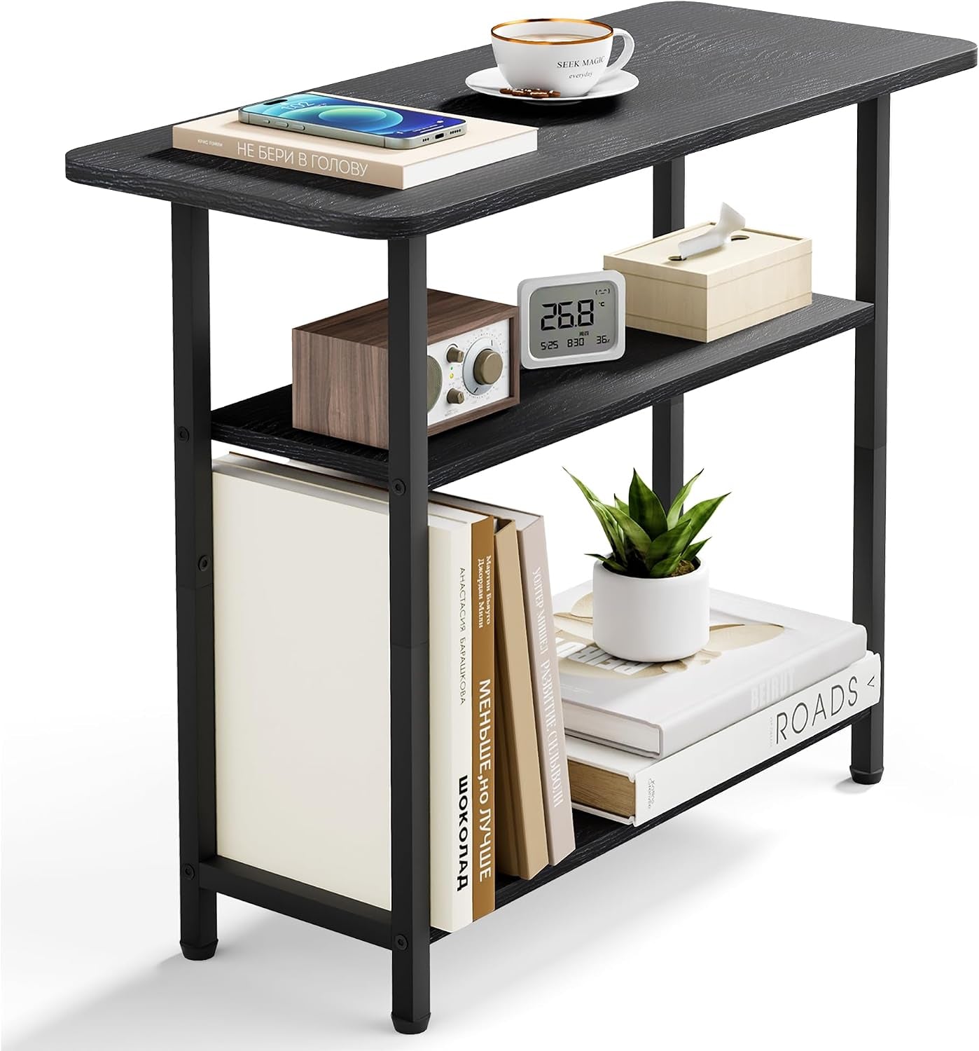 Three-tier narrow side table with black woodgrain shelves and black metal frame, styled with books, plant, clock, and cup
