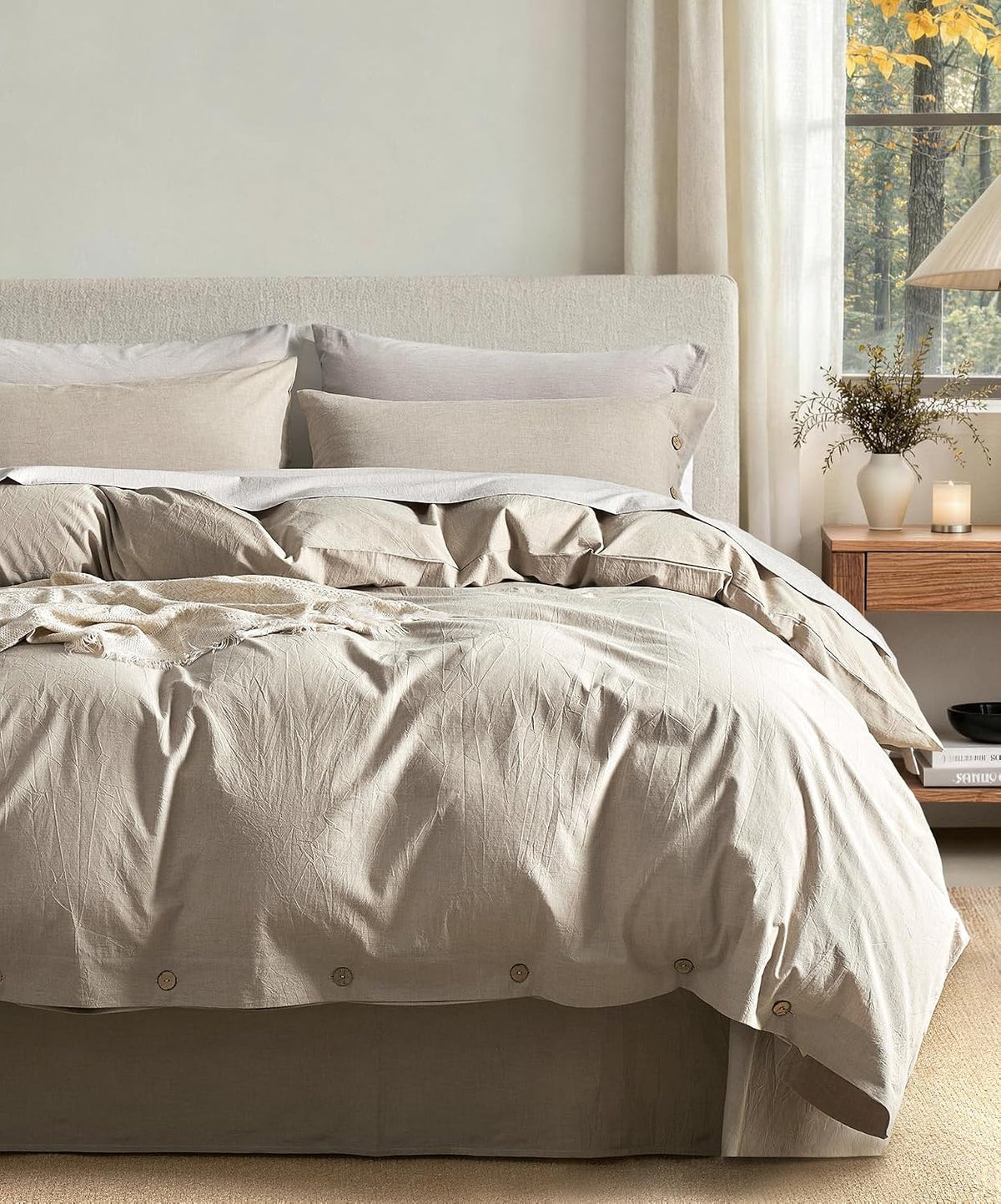 Bedroom styling with light beige washed-cotton duvet, layered pillows and a vase on a wooden nightstand
