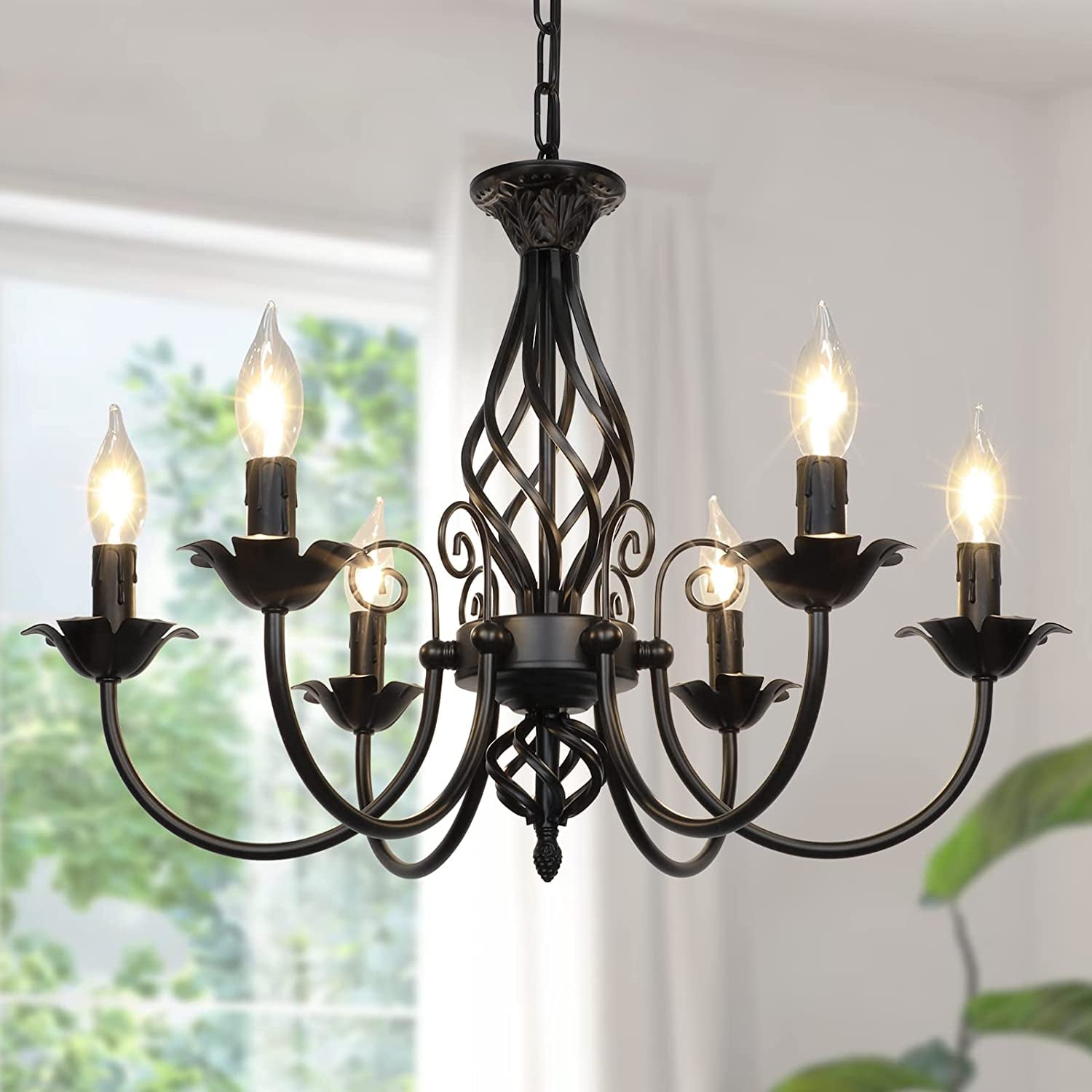 Black metal 6-light farmhouse candle chandelier close-up, lit candles and petal-shaped sockets, angled front view