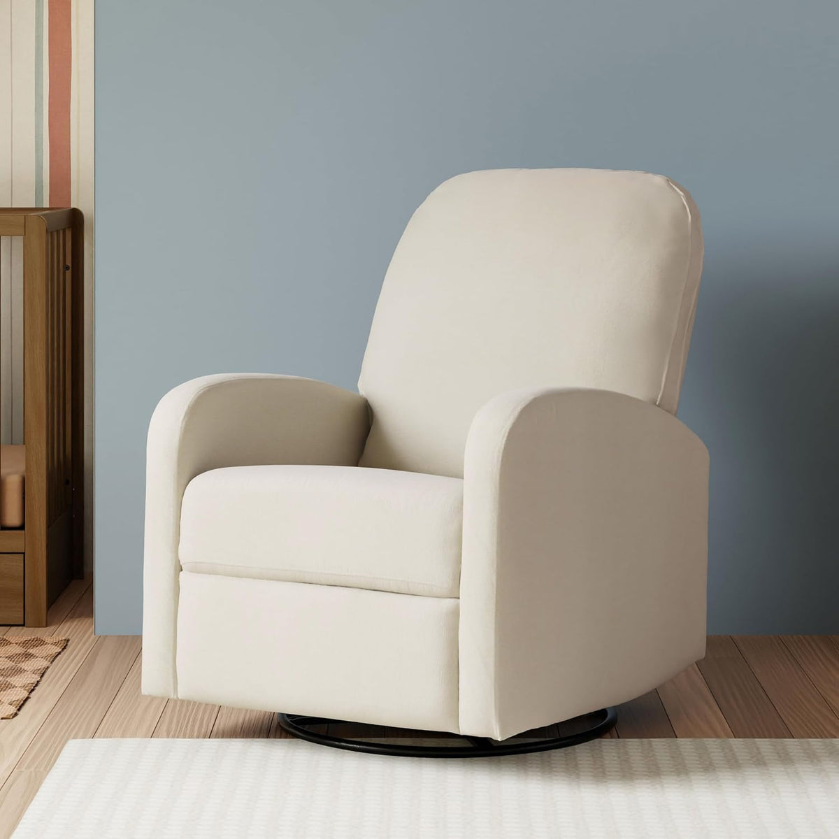 Three-quarter front view of a cream swivel recliner with rounded arms on a black circular base in a softly styled room.