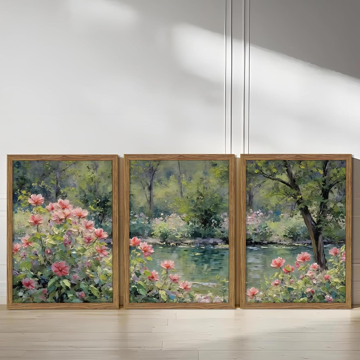 Three framed canvas panels leaning upright against a white wall on a light wood floor, front-facing view