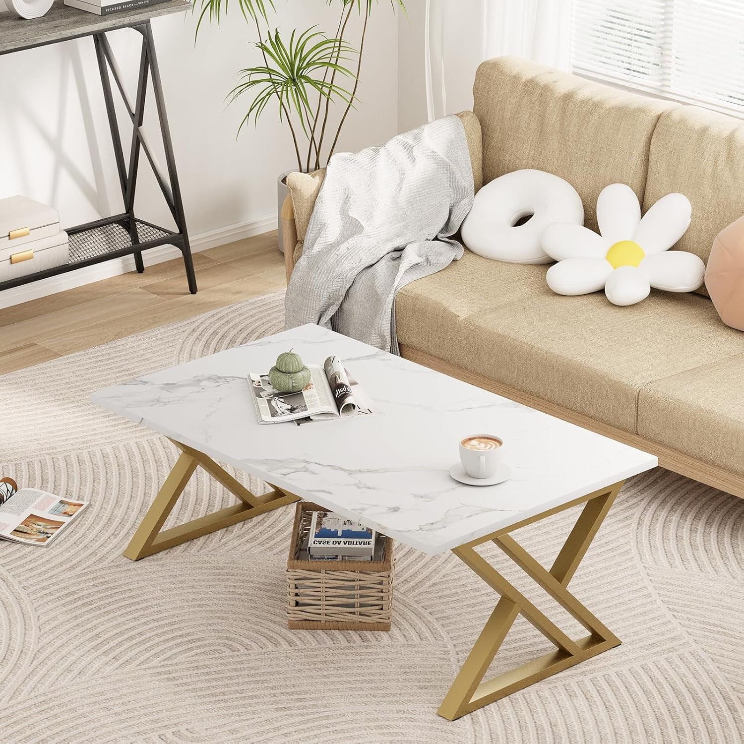 White faux marble top coffee table with gold X-legs in a bright living room beside a beige sofa