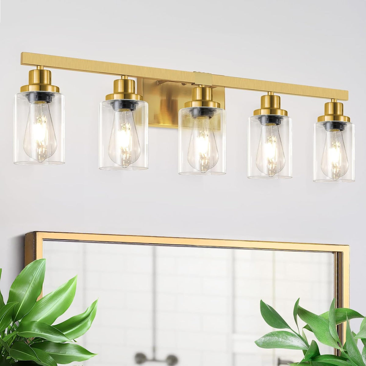 Brass five-light vanity light with clear glass shades mounted above a rectangular mirror