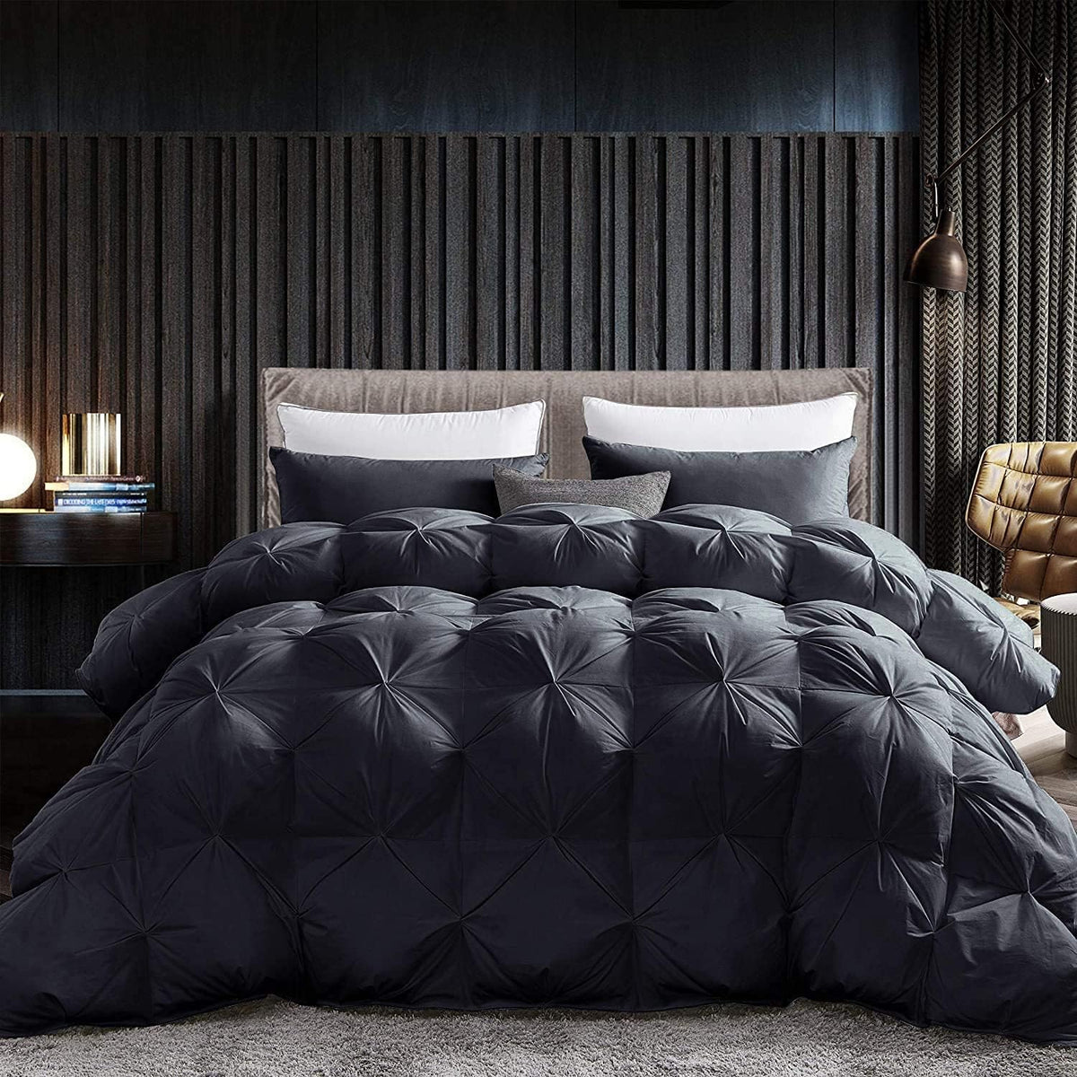 Low front view of a black pintuck comforter with textured headboard and dark paneled wall behind
