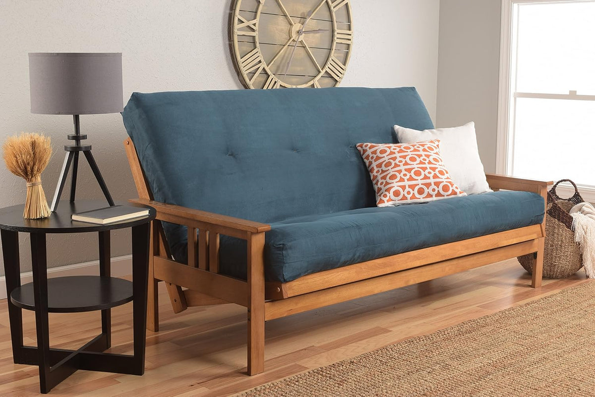 Full futon upholstered in teal fabric on a mission-style hardwood frame, styled with patterned and white throw pillows.
