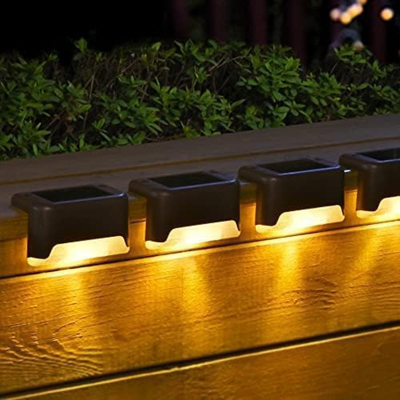 Row of brown solar step lights mounted on a deck railing casting a warm, even glow downward at night.