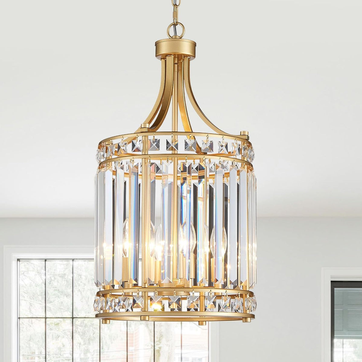 Gold-tone pendant chandelier close-up highlighting the warm metal finish and clear vertical crystal prisms.