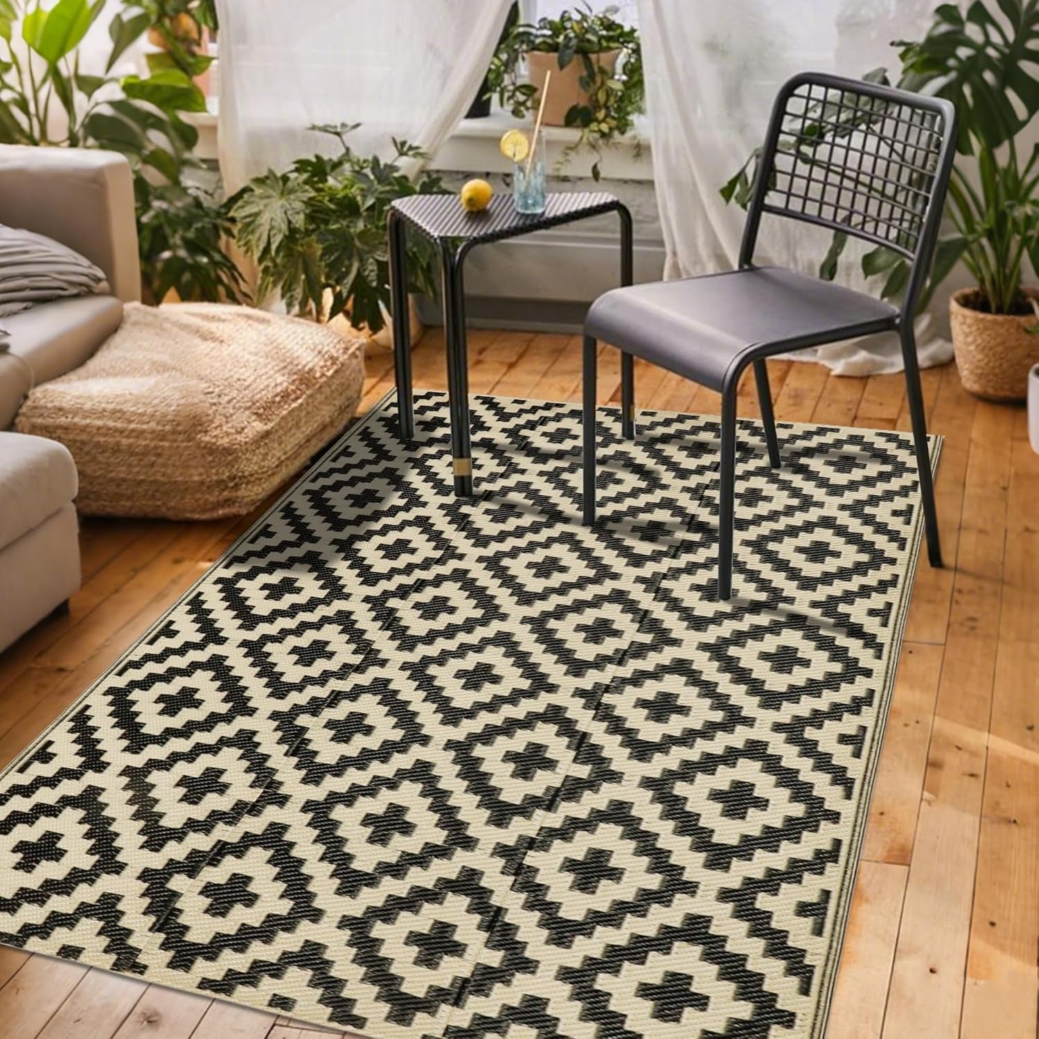 Small interior scene showing a black-and-cream geometric rug under a chair and small table by plants.