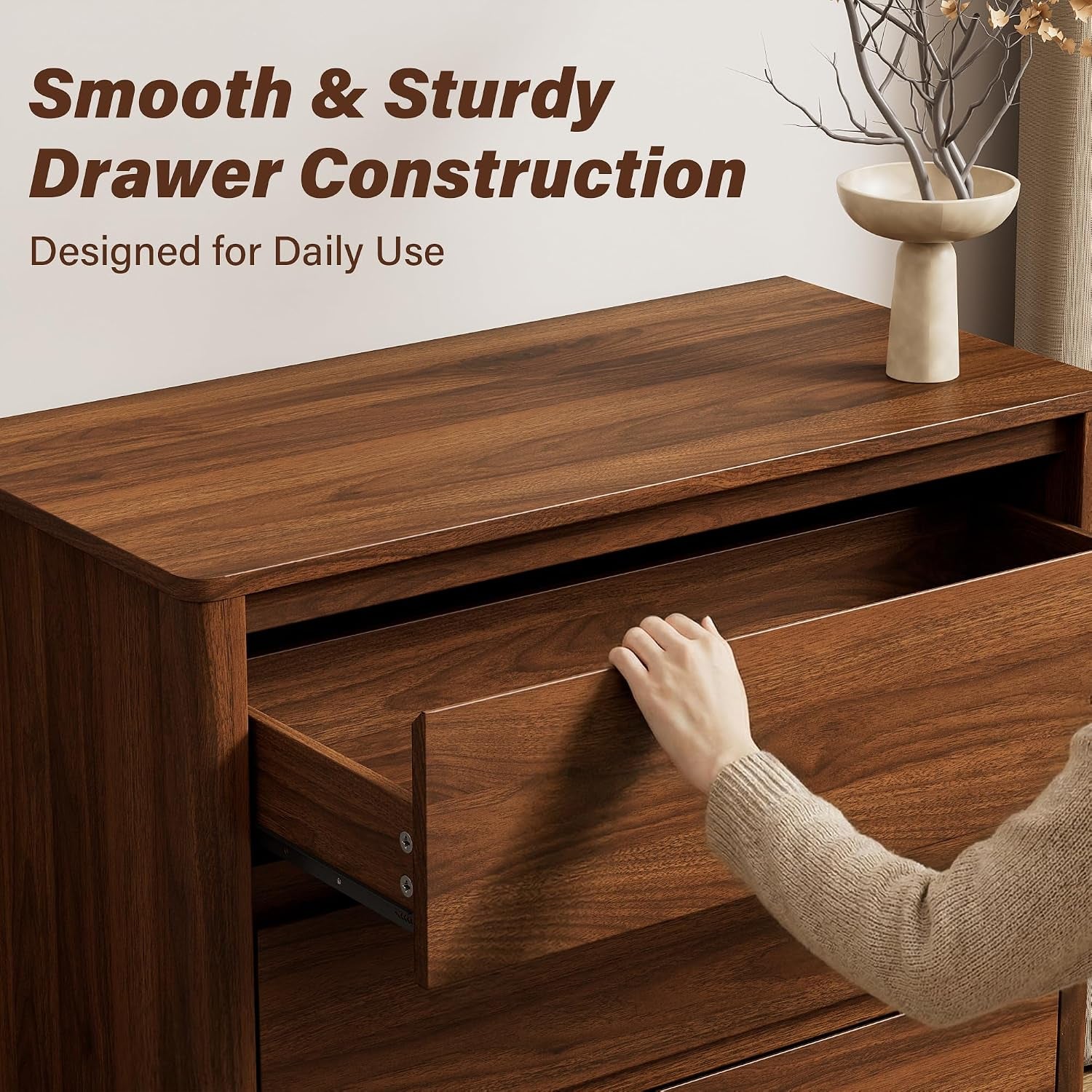Partial view of a hand opening a top drawer to show smooth drawer construction and hidden handle detail