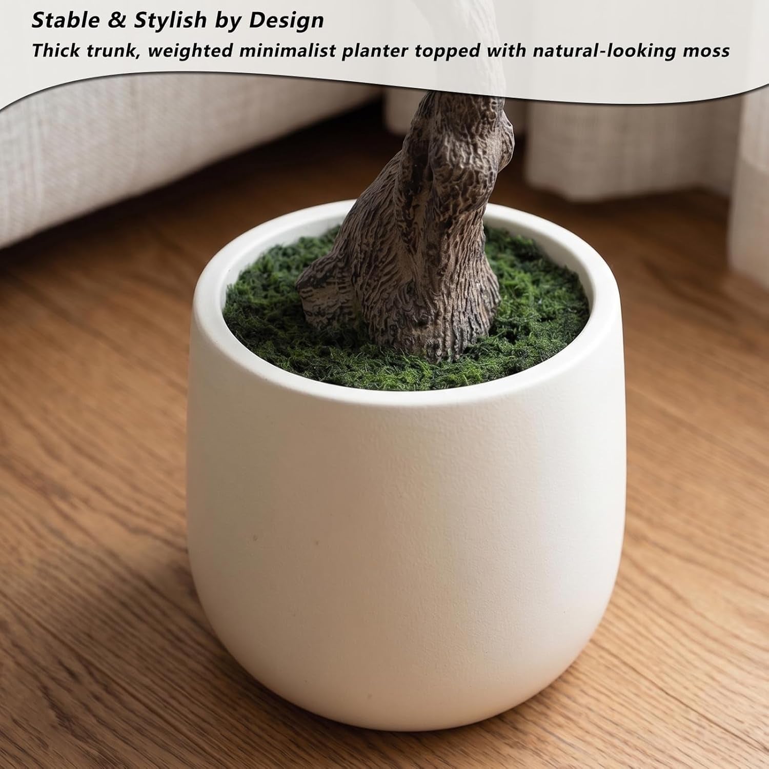 Detail of the white weighted planter showing artificial moss topping and the tree trunk base
