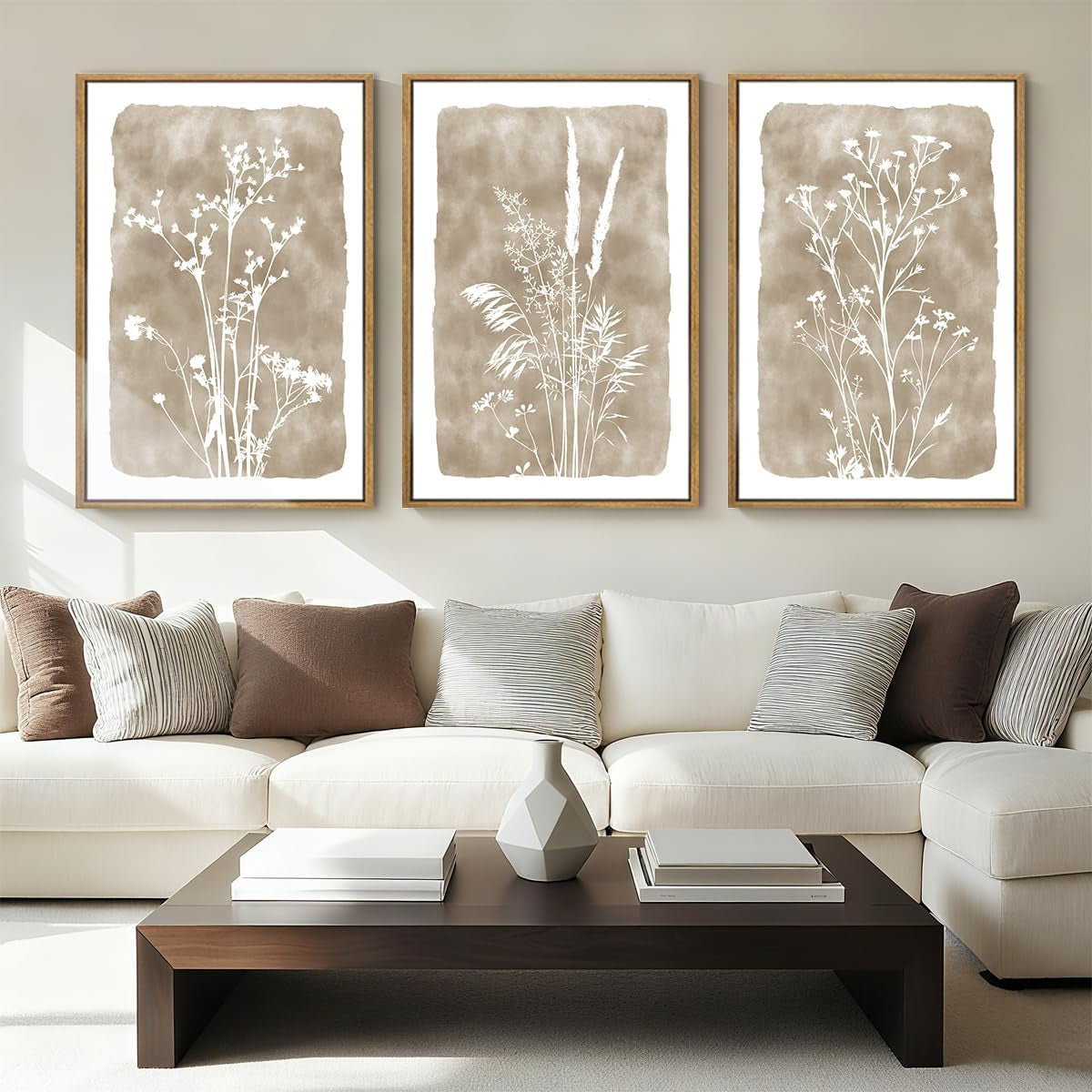 Triptych of white wildflower silhouettes on brown watercolor rectangles, each in a wood frame above a couch.