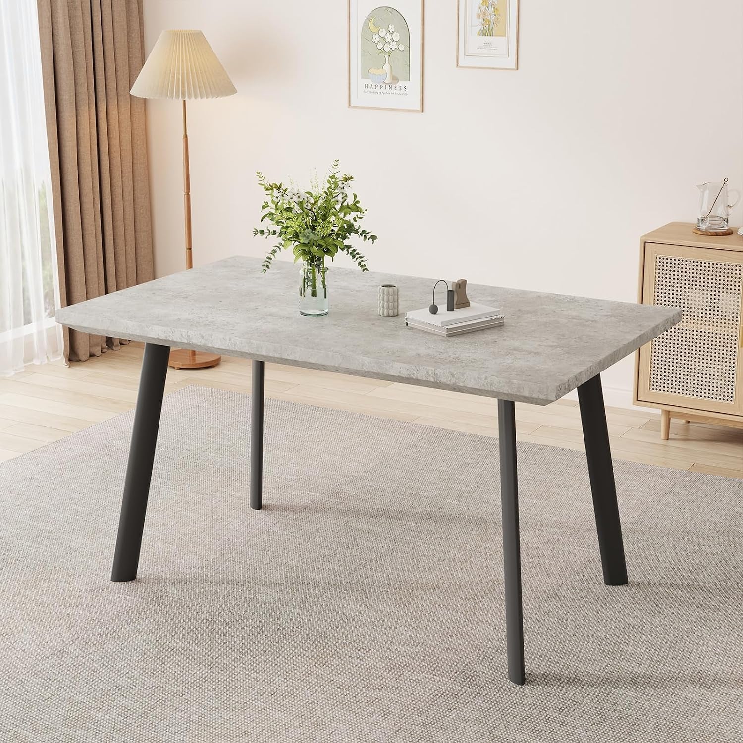 Close side view of a light grey rectangular tabletop with four angled black metal legs on a neutral rug.
