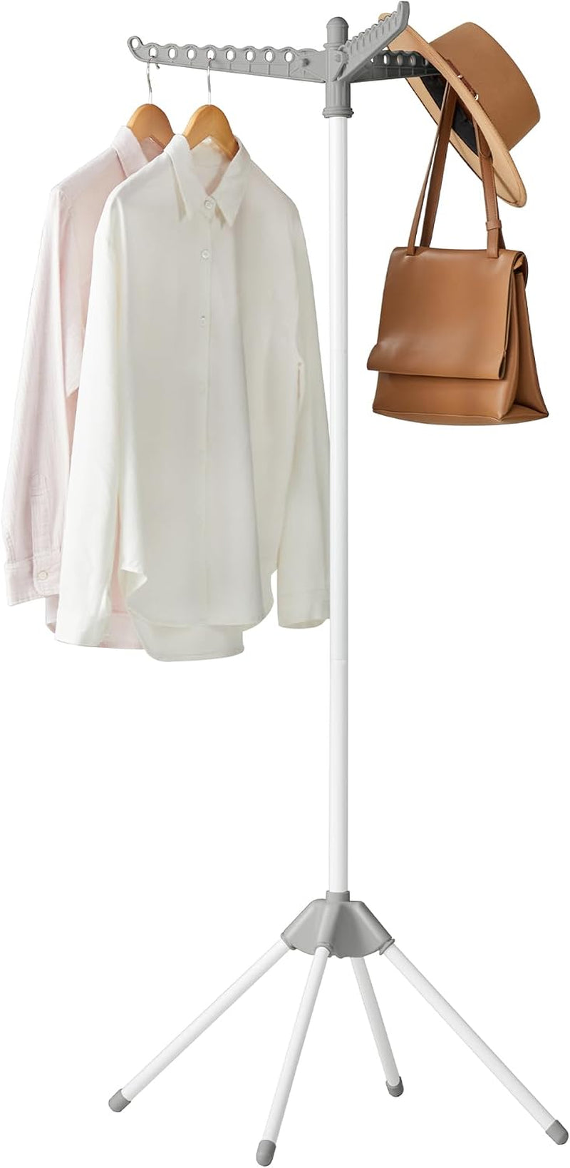 White freestanding drying rack with three folding arms, two button shirts and a tan bag and hat hanging.