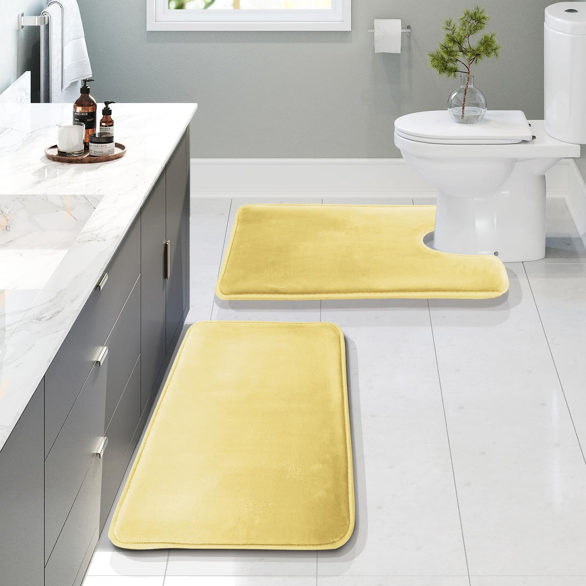 Angled bathroom shot with two long pale-yellow mats leading to a matching U-shaped mat by the toilet.
