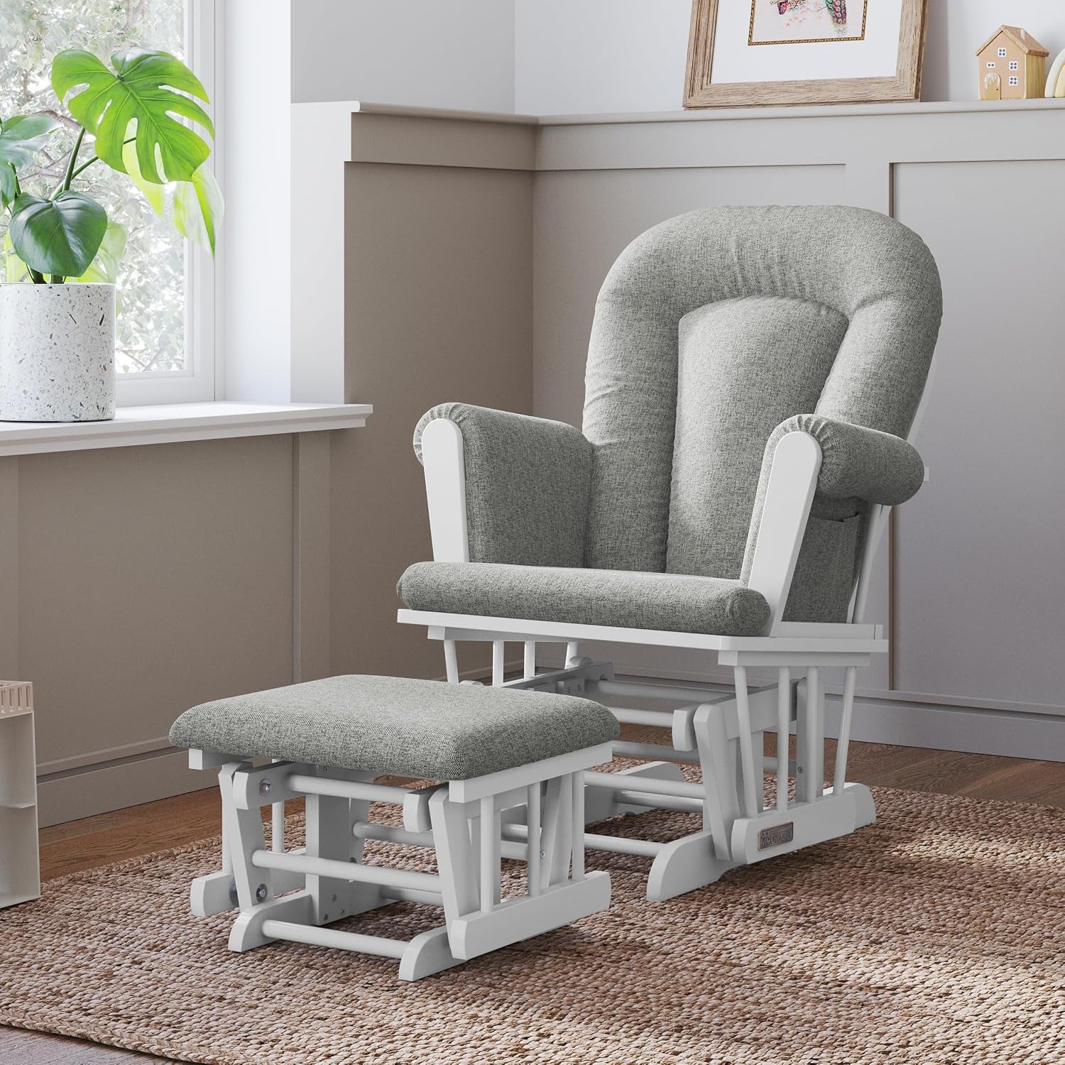 Glider chair and ottoman in a cozy corner with white frame and light gray cushions on a woven rug.