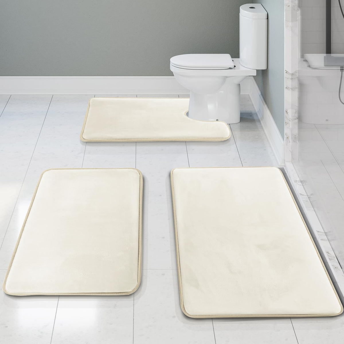 Three plush rectangular bath rugs laid on a white tile bathroom floor, one U-shaped rug at the toilet.