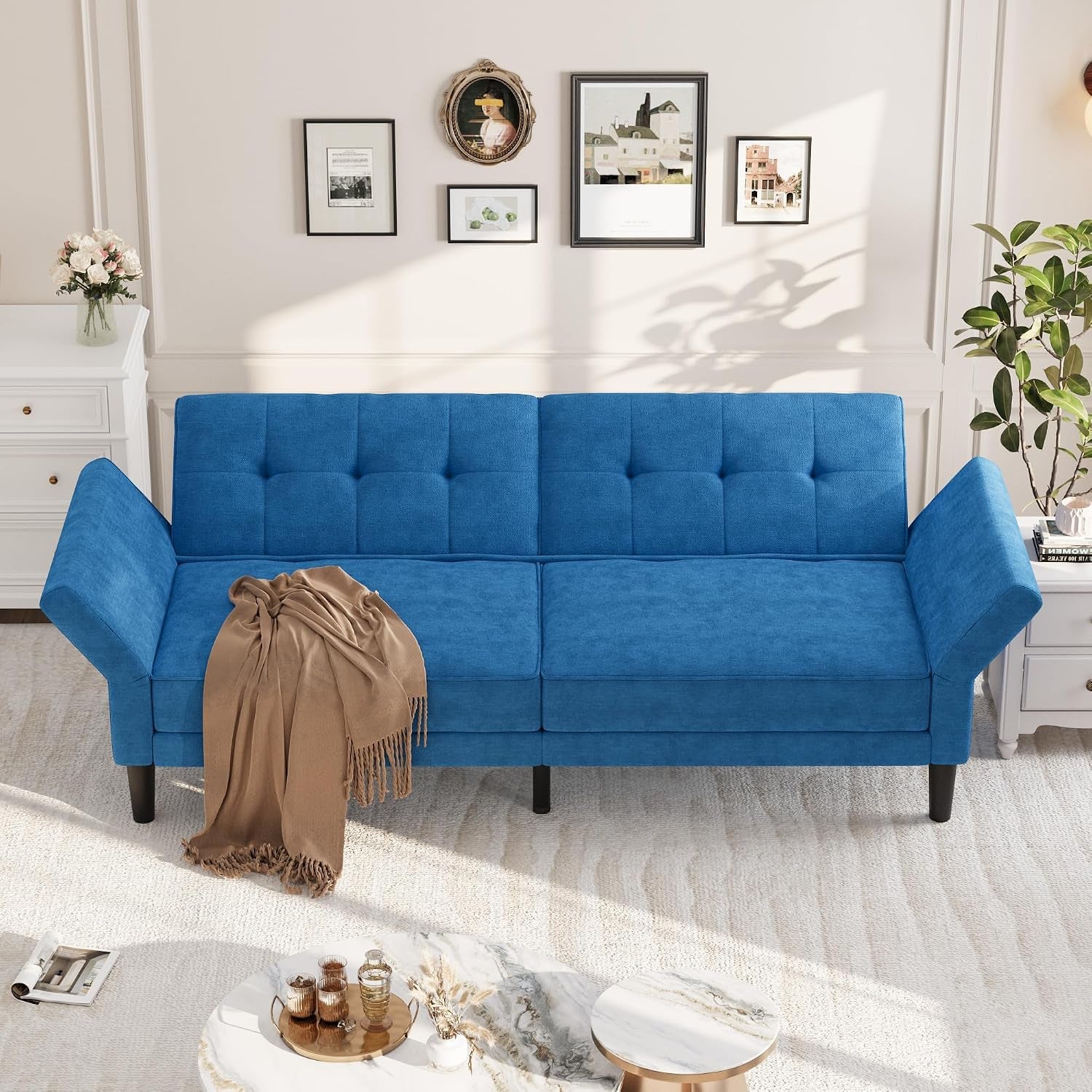 Blue futon with both armrests lowered to create a flat seating surface in a bright living room