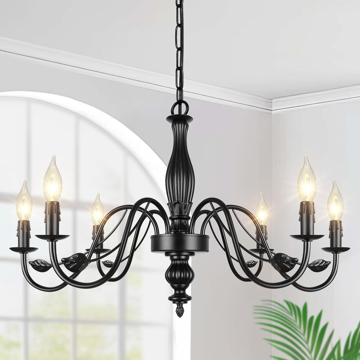 Close-up of matte black chandelier top, chain, and six curved arms with lit bulbs