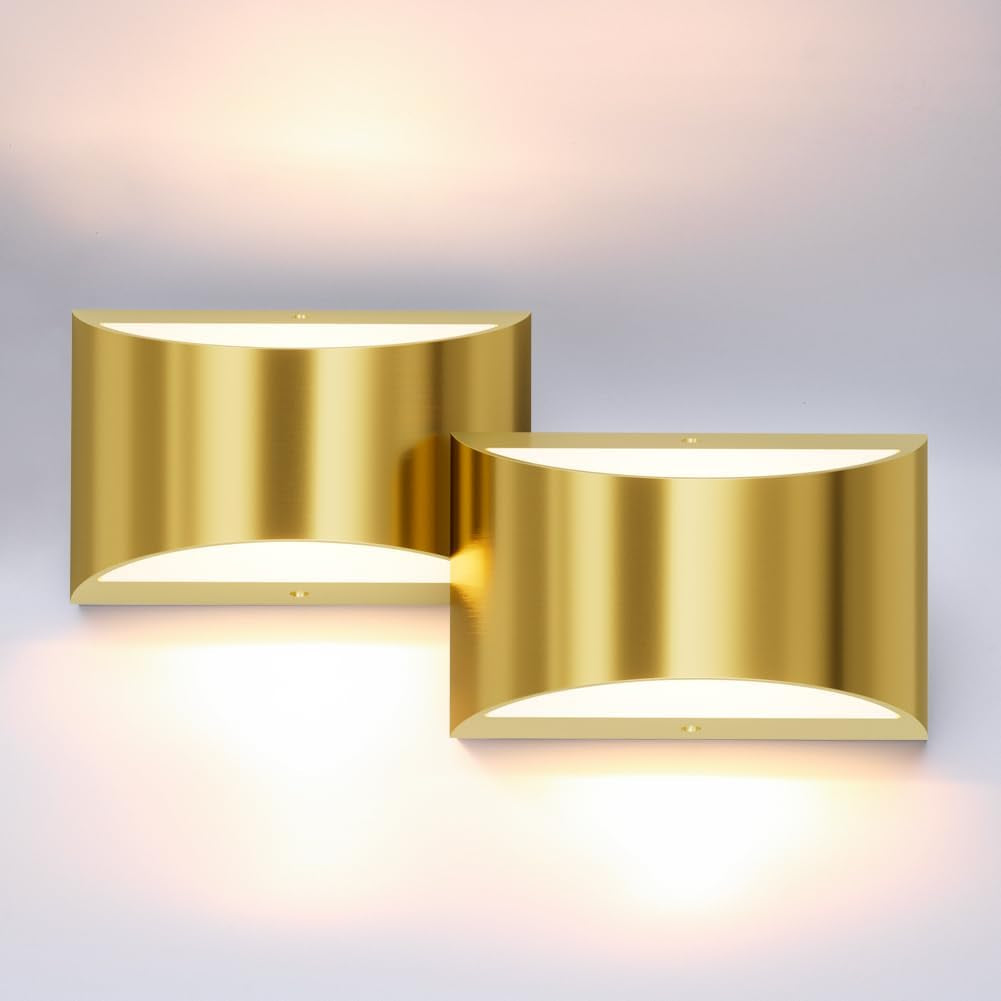 Two gold wall sconces displayed together on a pale wall, each casting warm uplight and downlight.